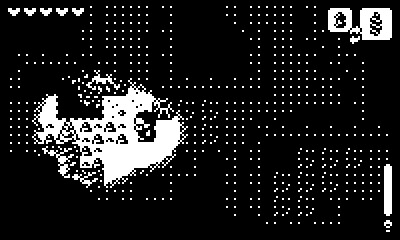 Screenshot from the game Ratcheteer, rendered in black and white pixels. A dark figure in a snowcap wanders through a cave with limited field of view, which we see from a top-down perspective. Only the area in front of the figure is lit up, revealing rocks, stalagmites, and craggy walls. The rest of the screen is mostly obscured by darkness, save for some traces of environmental shape rendered in sparse pixels.
